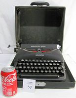 Front view of the Remington Rand Deluxe Model 5 typewriter open in its hard carrying case next to a soda can for scale.