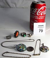 Photo showing four sterling rings, two bracelets, two necklaces with pendants and a coin for scale next to a can of Coca-Cola.