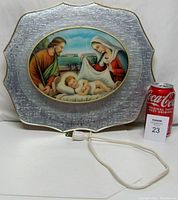 Front view of vintage light-up nativity scene icon showing baby Jesus, Mary, and Joseph with electrical cord and a can for size reference.
