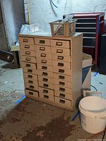Metal card catalog cabinet with multiple drawers and plastic baskets on top with electrical supplies