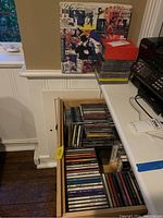Drawer full of CDs and cassette tapes from various artists, showing overall contents and storage location.