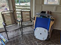 Four chairs arranged indoors near glass doors; three with brown metal mesh design and one blue fabric with built-in cup holders.