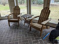 Wide view showing two Adirondack chairs flanking the folding side table