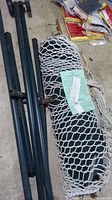 Hammock in white net-style fabric, poles and frame in metal, wrapped with instruction sheet.