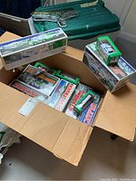 Box containing multiple Hess toy trucks and helicopter boxes including Monster Truck and Rescue Truck models.