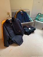 Navy insulated Carhartt work jackets, yellow rain slicker jackets, green plaid blankets folded next to white storage bins with teal lids and chrome hangers