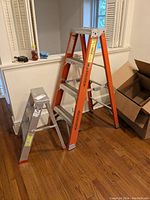 Two Werner ladders side by side, orange 48-inch ladder and smaller aluminum 24-inch ladder