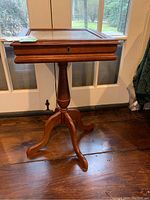 Front view of the wooden shadow box table with beveled glass top and three-legged pedestal base, showing the overall condition and structure.