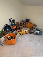 Photo of toys and games stored in orange bins, boxes, and scattered on carpeted floor