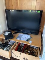 Toshiba 42-inch TV with remote, manuals, and miscellaneous cables on a wooden table