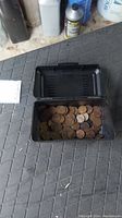 Black plastic box open with approximately 60 Wheat pennies inside, showing tops of coins with the wheat ear design.