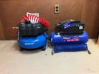 Both compressors side by side on floor with hoses attached
