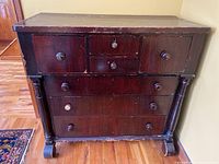 Front view of vintage bonnet cabinet showing six drawers and wood knobs with visible wear.