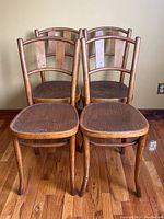Front view of all four wooden chairs showing the seats and backs together.