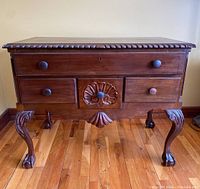 Front view of the Chippendale style chest showing drawer layout, carved details on legs and central drawer, and round wooden knobs.