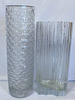 Both vases shown side by side on white background, highlighting clear textured glass vase next to Tapio Wirkkala vase