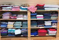 Front view of wooden shelving unit with folded pieces of assorted fabrics in various colors and patterns