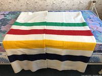 Full view of blanket folded across bed showing cream background and colored stripes