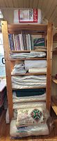 Wooden shelving unit loaded with folded batting layers and quilting books on top shelf