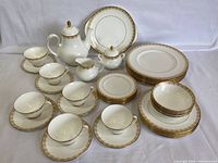 Front view of entire set showing dinner plates, bowls, teacups with saucers, teapot, creamer and sugar bowl