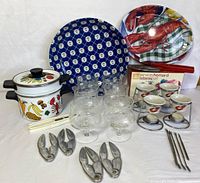 Full seafood serving set arranged on white surface showing all items together including lobster crackers, glasses, platters, pot, skewers, egg cups, and tongs.