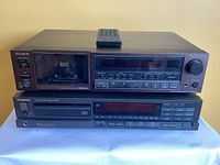 Front view of Sony stereo cassette deck stacked on top of Technics CD player with remote on top.