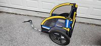 Side view of Bell 2 Child Bike Trailer showing yellow and blue color scheme and hitch arm for bicycle attachment.