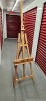 Full view of tall wooden artist easel showing structure and base