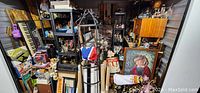 Overall view of storage unit with furniture pieces, artwork, and various collectibles stacked throughout