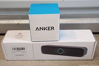 Photo showing the rectangular black Anker Bluetooth speaker box with a small blue and white Anker cube on top.