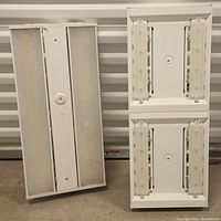 Two workshop fluorescent ceiling light fixtures, showing metal backing, lamp holders, and covers.