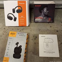 Four original boxes for the earbuds TrueFree, Bugani, OPC, Jesebang, showing front and packaging design.