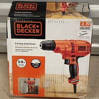 Photo of Black+Decker branded box for the 5.5 amp drill/driver showing product image, specifications including 3/8 inch keyless chuck, 0-1500 RPM speed range, and 30 day warranty.