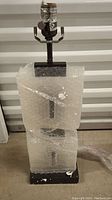 Photo of Flowdecor lamp base wrapped in bubble wrap showing gunmetal finish and alabaster detail
