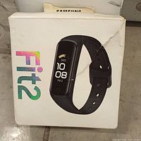 Damaged but original retail box for Samsung Galaxy Fit2 showing front with product image and branding.