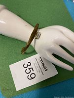Copper cuff bracelet displayed on a mannequin hand showing the bracelet's shape and size.