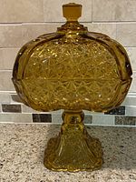 Amber EAPG Daisy & Button square compote with faceted knob lid on pedestal base, angled side view