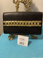 Front view of black leather purse featuring gold-tone chain link design across the front flap.