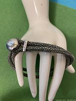 Leather bracelet displayed on a white mannequin hand showing textured speckled pattern and silver-toned ZINZI clasp.