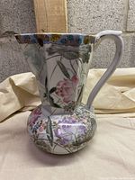 Full view of vintage Asian porcelain watering jug showing overall shape, handle, and painted floral and bird design with gold leaf edging