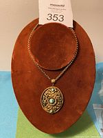 Full view of the vintage brass necklace displayed on a brown velvet stand showing chain length and pendant style.