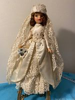 Front view of the hand made bridal doll showing the full wedding attire, lace veil, and bouquet.