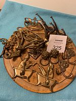 Top view of assorted vintage brass handles and hangers on round wooden board.