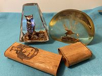 Photo showing both Lucite paperweights (owl and pheasant) and the cedar box with Che Guevara logo on a blue backdrop.