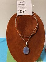 Full view of the necklace displayed on a brown velvet bust showing the 24-inch silver chain and oval moonstone pendant.