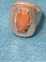 Close-up of the vintage sterling silver ring with pink iridescent stone on a blue background showing ring top and stone detail.
