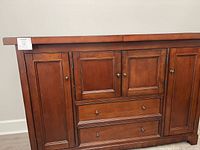Full front view of the dark brown wooden bar cabinet showing drawers, cabinets, and doors.