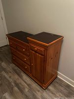 Side angle photo of Bassett changing table/dresser showing drawer faces, cabinet door, and wood finish.
