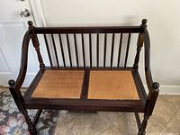 Front view of the wooden bench showing slatted backrest and woven seat panels.
