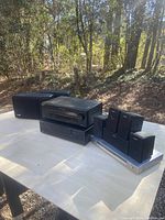 Sony receiver, Kenwood CD player, Bose speakers including subwoofer and satellite speakers, Sony surround sound receiver, and Sony DVD player arranged on a table outdoors.